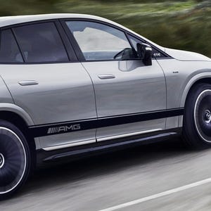 以下が含まれることがあります： 銀色のSUVで、黒いアクセントと側面に「AMG」の文字があります。車は舗装された道路を走っています。