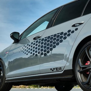 May include: A gray car with black honeycomb-patterned decals on the side. The car has black wheels and a black side skirt with the word "TCR" printed on it.