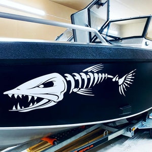 Könnte beinhalten: Ein schwarzes Aluminiumboot mit einem weißen Fischskelett-Aufkleber an der Seite. Das Boot steht auf einem Anhänger mit dem Schriftzug "RESBO" an der Seite.