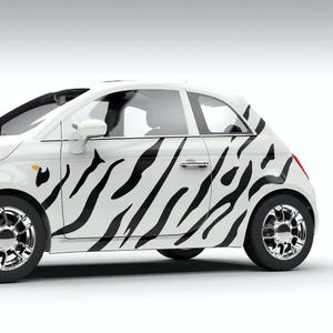 Op de afbeelding: Een witte auto met een zwart zebraprintontwerp aan de zijkant. De auto heeft chromen wielen en een zwarte deurgreep.