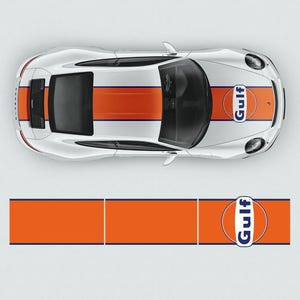 May include: A white sports car with a blue and orange racing stripe down the centre of the car. The car has a Gulf logo on the side and the back. The car is on a white background.