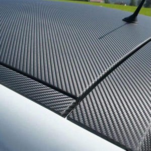 Puede incluir: Primer plano del techo de un coche con un patr&oacute;n de fibra de carbono. El material texturizado negro y gris se aplica en un tejido diagonal, creando una textura visual. El techo del coche tambi&eacute;n tiene una antena negra.