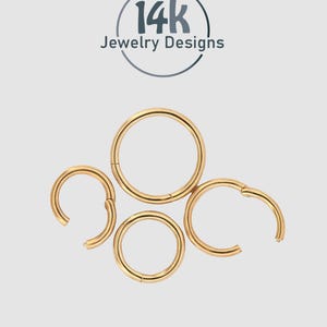 Op de afbeelding: Gouden oorringen in verschillende maten, sommige open en sommige gesloten, tegen een lichtgrijze achtergrond. De oorbellen maken deel uit van de "14k Jewelry Designs" collectie, zoals aangegeven door het logo bovenaan.