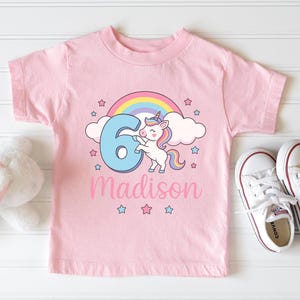 May include: Pink t-shirt with a rainbow, a unicorn holding the number 6, and the name Madison.