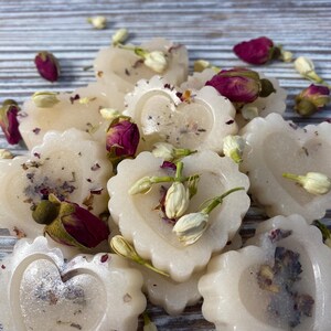 May include: A collection of heart-shaped wax melts with dried flowers and herbs. The melts are white and have a subtle shimmer. The flowers are pink and white.