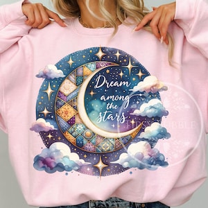 Może przedstawiać: Jasnoróżowa bluza z niebiańskim wzorem. Wzór zawiera półksiężyc, gwiazdy i chmury, ze słowami "Dream among the stars". Księżyc jest wypełniony wzorem patchworkowym. Na górze wydrukowano "Digital Download Only".