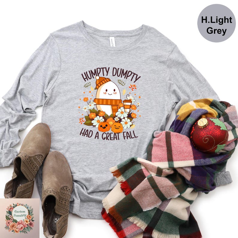 a gray long-sleeved t-shirt with a graphic design, a pair of brown boots, a colorful plaid scarf, and a red ornament.