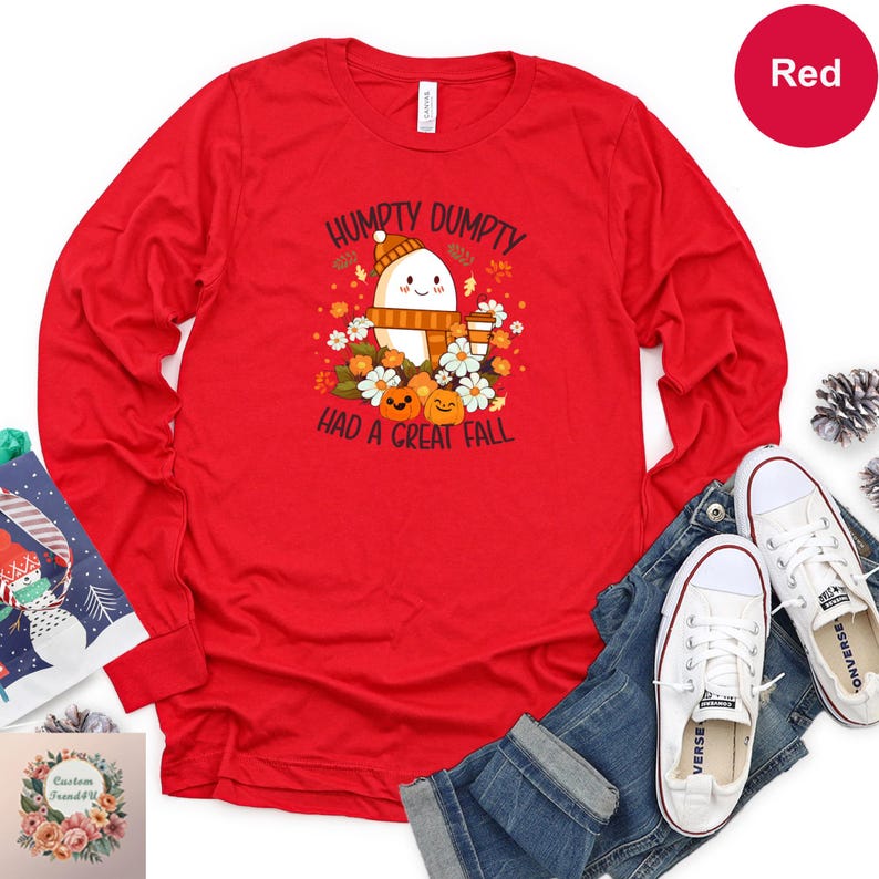 a red long-sleeved t-shirt with a cartoon character and text, along with a pair of jeans and white sneakers, all laid out on a white background.