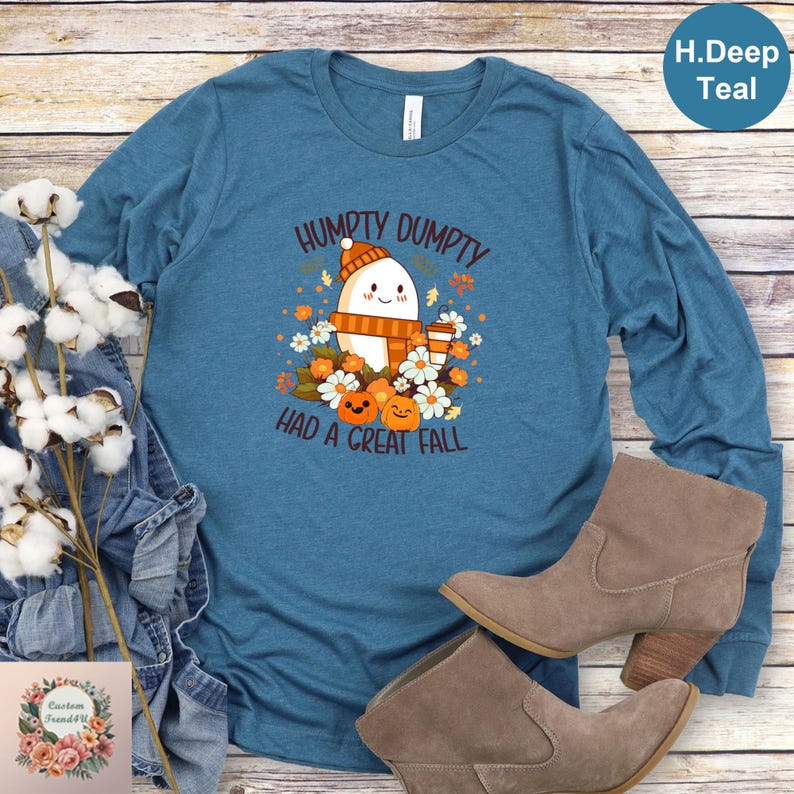 a blue long-sleeved t-shirt with a graphic design, a pair of brown boots, and some flowers on a wooden surface.
