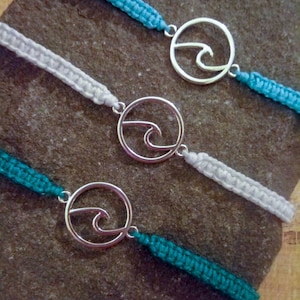 May include: Three friendship bracelets with turquoise and white cord and silver wave charm.