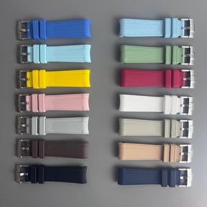 Op de afbeelding: Een set van 10 verschillende gekleurde horlogebandjes. De bandjes zijn gemaakt van een getextureerd rubber materiaal en hebben een zilveren gesp. De kleuren omvatten blauw, lichtblauw, geel, roze, wit, lichtgrijs, bruin, beige, donkerblauw en zwart.