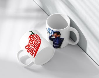 May include: Two white ceramic mugs. One mug features a red chili pepper design with the words "Smooth Operator" in red. The other mug has a blue and white design with a person in a blue uniform. Both mugs have a white handle.