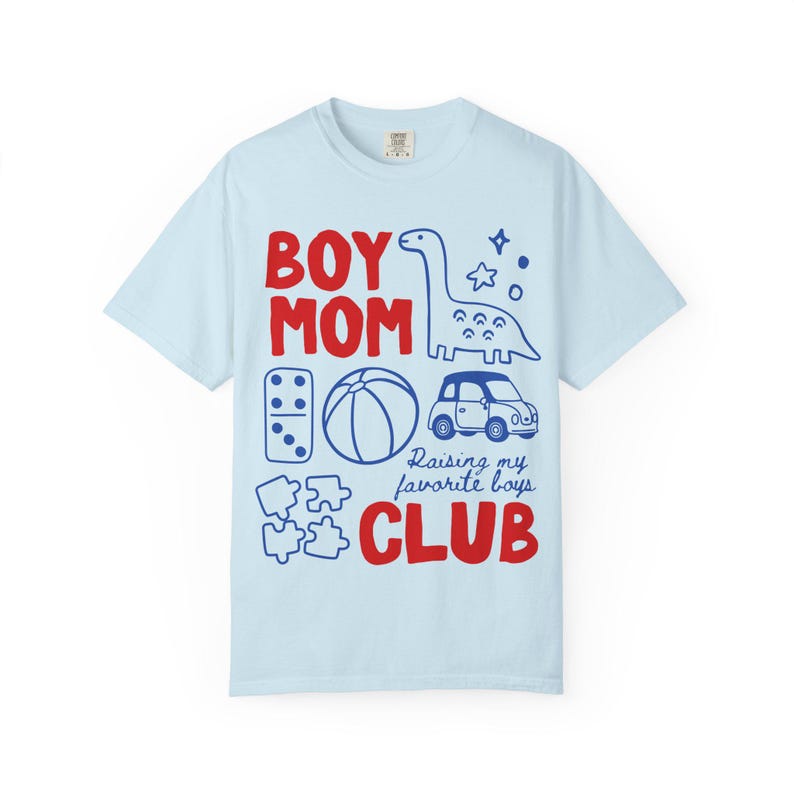 Light blue Comfort Colors boy mom club shirt featuring dinosaur toy car puzzle ball illustrations raising my favorite boys slogan soft motherhood aesthetic graphic tee gift for moms of boys ships without price tag