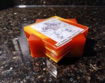 Könnte beinhalten: Ein Stapel quadratischer Untersetzer mit Fußballmotiv. Jeder Untersetzer zeigt ein Spielerbild und den Text "Len Dawson, Super Bowl IV MVP". Die Untersetzer sind orange und gelb mit roten Stützen.