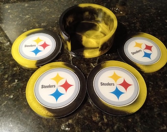 May include: Set of four black and yellow coasters featuring the Pittsburgh Steelers logo. The coasters are made from resin and have a glossy finish.