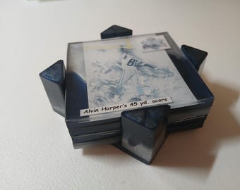 May include: A set of square coasters featuring a football player image and the text "Alvin Harper's 45 yd. score." The coasters are encased in clear resin with dark blue accents and corner supports.