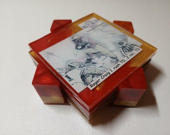 May include: A set of four square coasters with a football theme. Each coaster features a football action sketch and the text "Roger Craig 1 rush TD, 2 rec. TD" on a red and gold resin base. The coasters are approximately 4 inches square.