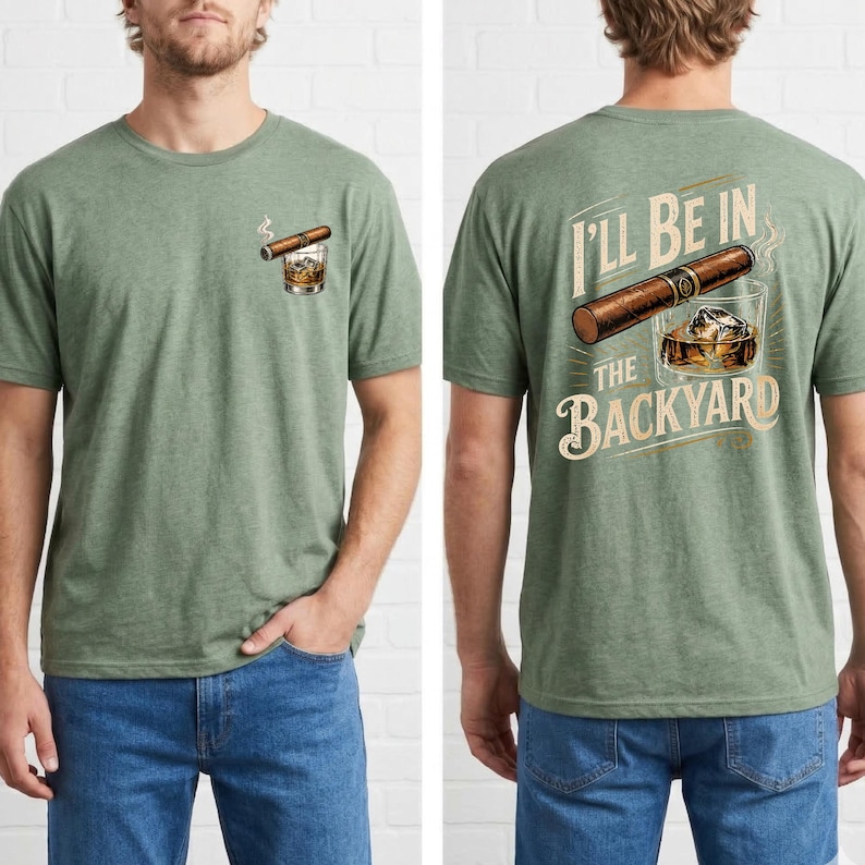 May include: A heather green short-sleeve t-shirt featuring a small graphic on the front left chest of a cigar and a glass of whiskey. The back displays a large graphic of a cigar and a glass of whiskey with the text I'LL BE IN THE BACKYARD.