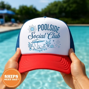 May include: A red, white, and blue trucker hat with the text "Poolside Social Club" in blue script. The hat features a sun graphic and illustrations of lounge chairs, plants, and an umbrella. The hat is held up by a person.
