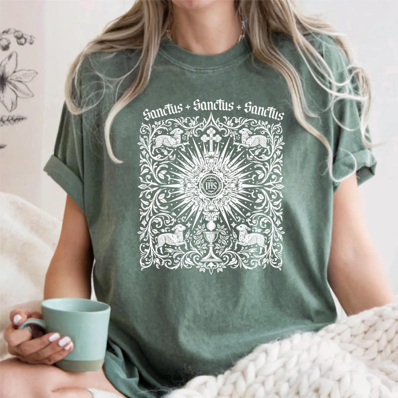 A woman wearing a green t-shirt with a white graphic design on it, holding a teacup.