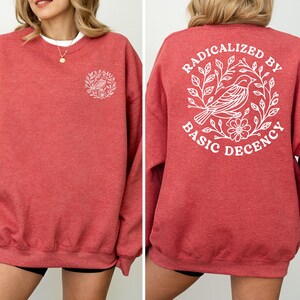 A red sweatshirt with a white design on the back, featuring a bird and floral elements.