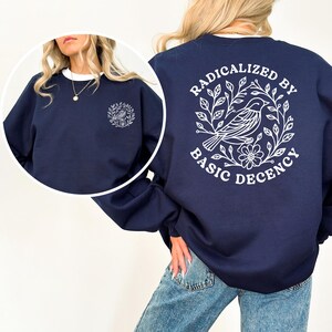 A woman wearing a navy blue sweatshirt with a white graphic design on the back.