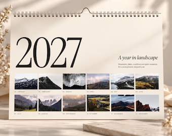 Peut inclure: Un calendrier mural 2027 intitulé A year in landscape, présentant douze petites photographies rectangulaires de montagnes, lacs et côtes. Le calendrier a un fond crème, du texte noir et une reliure métallique argentée en haut.