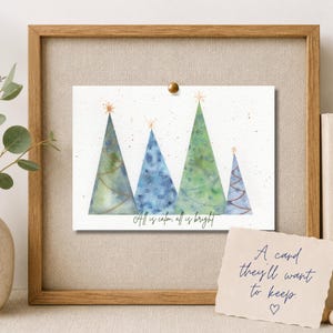 Pu&ograve; includere: Un biglietto d'auguri rettangolare con un'illustrazione ad acquerello di quattro alberi di Natale stilizzati in tonalit&agrave; di verde e blu, sormontati da stelle dorate. Il testo "All is calm, all is bright" &egrave; stampato in nero in basso.