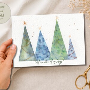 Pu&ograve; includere: Un biglietto d'auguri rettangolare con un'illustrazione ad acquerello di quattro alberi di Natale stilizzati in tonalit&agrave; di verde e blu, sormontati da stelle dorate. Il testo "All is calm, all is bright" &egrave; stampato in nero in basso.