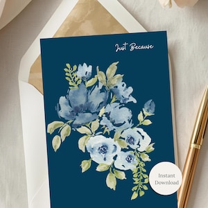 Op de afbeelding: Een marineblauwe wenskaart met een aquarel bloemenontwerp in blauw- en wittinten, met de tekst "Just Because". Een gouden pen ligt naast de kaart en een envelop is zichtbaar.
