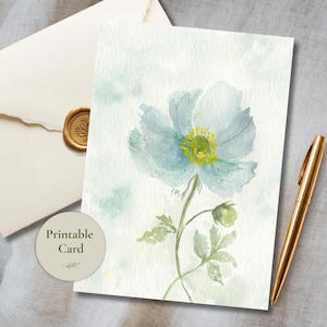 May include: A rectangular greeting card featuring a watercolor illustration of a single light blue flower with a yellow center, green stem, and leaves. A circular label with the text Printable Card is present, alongside a gold pen and envelope.