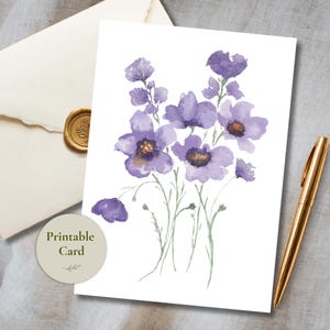 Puede incluir: Una tarjeta de felicitación rectangular con una ilustración en acuarela de flores moradas con tallos verdes sobre un fondo blanco. La tarjeta está colocada junto a un bolígrafo dorado y un sobre color crema con un sello de cera dorado. Una etiqueta circular dice Printable Card.
