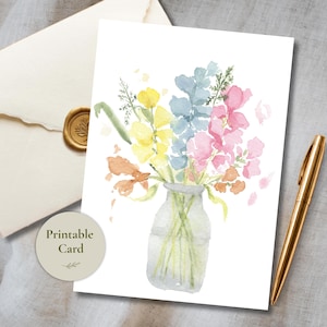 May include: A rectangular card featuring a watercolour illustration of a bouquet of yellow, blue, pink, and orange flowers in a clear glass vase. The card includes the text Printable Card in a circular badge and is accompanied by a gold pen.