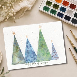 Pu&ograve; includere: Un biglietto d'auguri rettangolare con un'illustrazione ad acquerello di quattro alberi di Natale triangolari in tonalit&agrave; di verde e blu, ciascuno sormontato da una stella dorata. Il testo "All is calm, all is bright" &egrave; stampato in nero.
