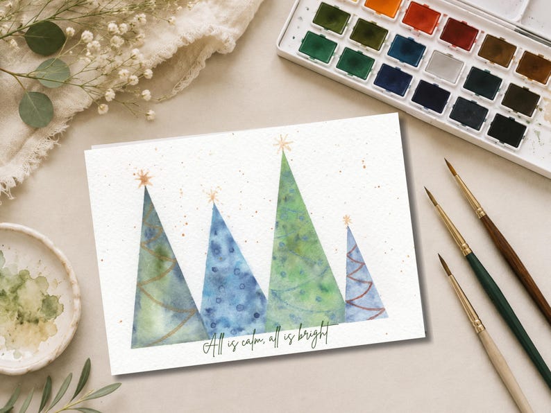Pu&ograve; includere: Un biglietto d'auguri rettangolare con un'illustrazione ad acquerello di quattro alberi di Natale triangolari in tonalit&agrave; di verde e blu, ciascuno sormontato da una stella dorata. Il testo "All is calm, all is bright" &egrave; stampato in nero.