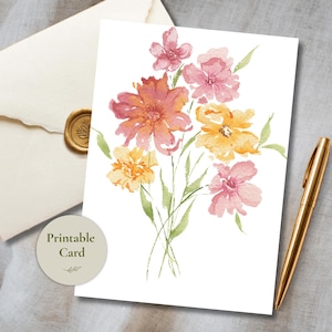 Puede incluir: Una tarjeta rectangular con una ilustración en acuarela de un ramo de flores con pétalos rosas, naranjas y amarillos y tallos verdes. Un sobre color crema con un sello de cera dorado y un bolígrafo dorado se encuentran junto a la tarjeta.