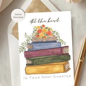 May include: A greeting card with a watercolor illustration of a stack of books topped with flowers and greenery. The text "All the best" and "In Your Next Chapter" are written on the card. A gold pen rests beside the card.