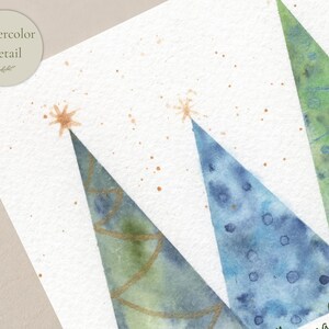 Pu&ograve; includere: Un'illustrazione ad acquerello su carta ruvida che raffigura tre forme di alberi triangolari in tonalit&agrave; blu e verdi. Gli alberi sono decorati con linee e punti dorati, sormontati da stelle dorate e circondati da piccoli schizzi di vernice.