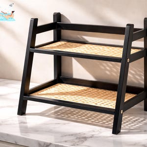 May include: A black wooden shelf with two levels, featuring woven rattan inserts. The frame is a dark color, and the shelf is set against a light-colored wall. The text "FRESH LOOK by NATHAN" is in the top left corner.