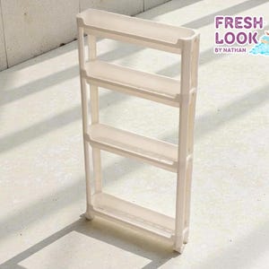 May include: A narrow, off-white, four-tiered rolling storage cart. The cart has a rectangular frame with four shelves and small wheels. The text "FRESH LOOK by NATHAN" is in the upper right corner.
