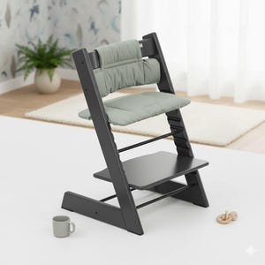 Puede incluir: Una silla alta de madera gris oscuro con un coj&iacute;n acolchado para el asiento y el respaldo en color verde salvia. La silla tiene un dise&ntilde;o ajustable con m&uacute;ltiples ranuras a lo largo de los soportes laterales, base plana y reposapi&eacute;s.