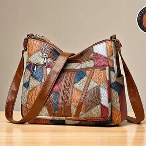 May include: A patchwork crossbody bag with a brown leather strap. The bag features a variety of colors and textures, including red, blue, and orange. It has multiple zippered compartments and a braided detail on the front.