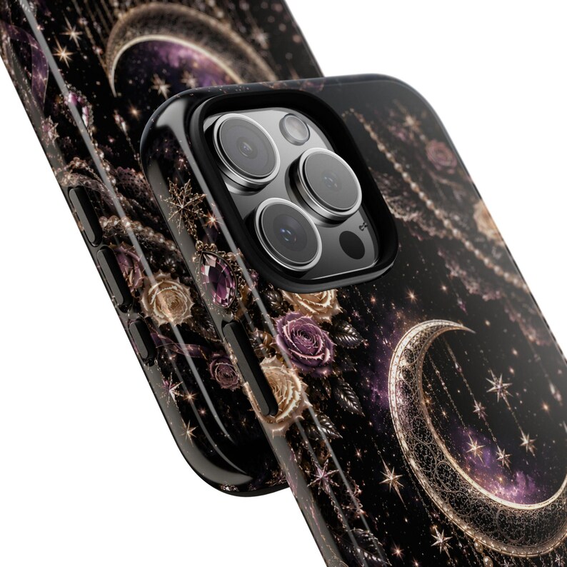 May include: Black phone case with a celestial design featuring a crescent moon, stars, and roses. The case has a glossy finish and a black border. The design incorporates shades of purple, gold, and white.