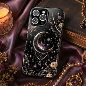 May include: Black phone case with a celestial design featuring a crescent moon, stars, and beaded accents. The case has a glossy finish and is surrounded by gold-colored jewelry and dried flowers. A lit candle sits in a glass holder.