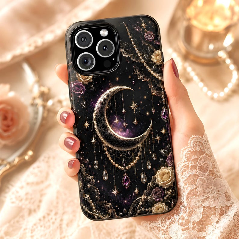 May include: Black phone case featuring a crescent moon, stars, and floral accents. The design includes gold and purple details, with a celestial theme. The case has a glossy finish and a decorative, ornate style.