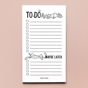 May include: A white rectangular notepad with black ink illustrations and text. The top section is labeled TO DO with a cat and bird. The bottom section is labeled MAYBE LATER with a cat and mouse. It features lined rows with checkboxes.