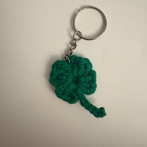 May include: A green crocheted four-leaf clover keychain with a silver metal ring.