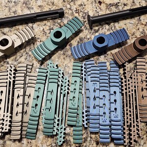 May include: A set of 3D printed plastic parts in various colors, including brown, blue, and green. The parts are designed for a specific purpose, possibly for a hobby or craft project. The parts are arranged on a textured surface.