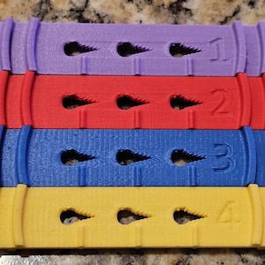 May include: Four colorful plastic strips with numbers 1 through 4 printed on them. Each strip has three holes in a row.