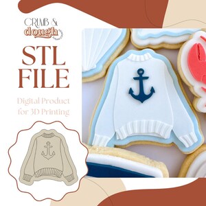 Op de afbeelding: Een afbeelding met een verzameling koekjes met een nautisch thema. Eén koekje heeft de vorm van een witte trui met een blauwe anker, omlijnd in blauw. De koekjes zijn versierd met blauwe en witte glazuur. De tekst "STL FILE" en "Digital Product for 3D Printing" zijn ook zichtbaar.